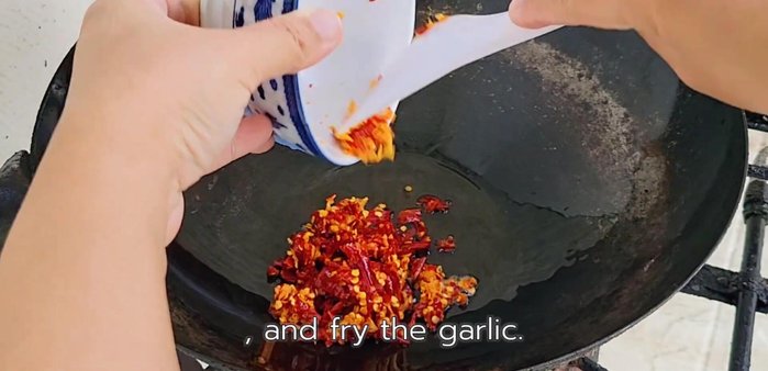 Add the pounded chili and garlic mixture to the pan and stir-fry until fragrant.