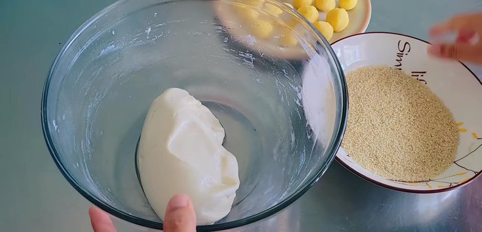 Divide the dough into portions, flatten each piece, add a filling ball, and seal it.