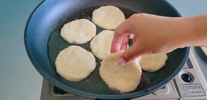 Fry the sesame snacks in hot oil over low heat, flipping frequently until golden brown and crispy.