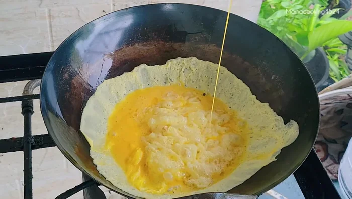 Pour in the beaten eggs and spread them evenly. Reduce heat slightly to prevent burning.