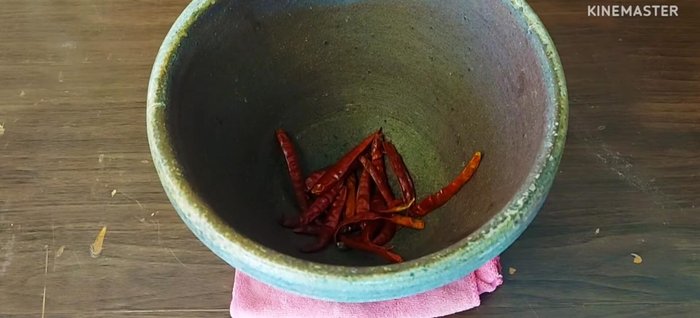 In a mortar and pestle, pound dried chilies.