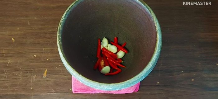 Pound red chilies, garlic, and 1 teaspoon of curry paste until finely ground. (The chilies are pounded to adjust spiciness and enhance color during stir-frying.)