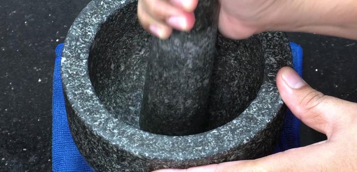 Pound black pepper, red chili peppers, and garlic in a mortar and pestle until crushed.