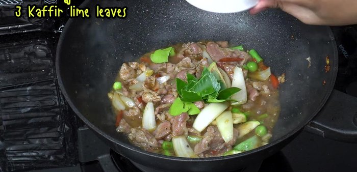 Add kaffir lime leaves, young peppercorns, green and red chili peppers. Stir-fry on high heat until cooked.
