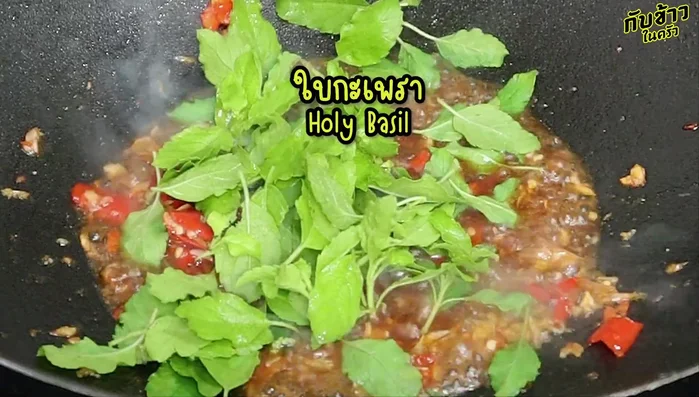 Stir-fry the holy basil leaves over high heat until fragrant.