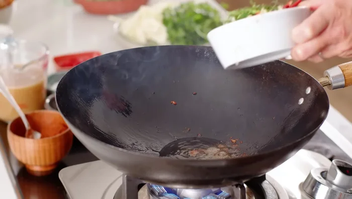 Heat wok on high heat. Add aromatics (onion, ginger, lime leaves) and cook until fragrant. (431.24)