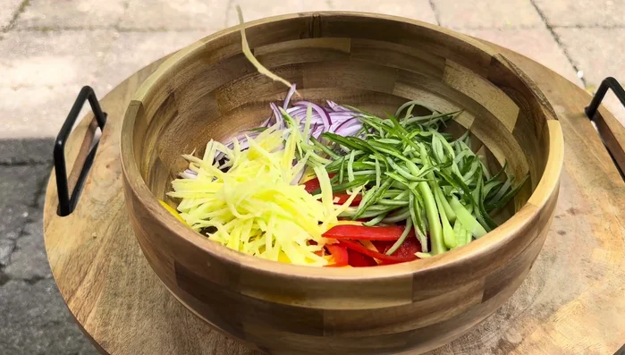 Combine the sliced vegetables in a salad bowl.