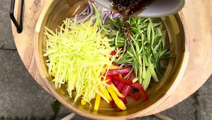 Pour the dressing over the vegetables. Season with a pinch of salt and a sprinkle of sugar.