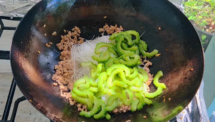 Add glass noodles (previously soaked), bitter melon, seasoning powder, soy sauce, oyster sauce, and sugar. Stir-fry until well combined. Add water if needed to prevent dryness.