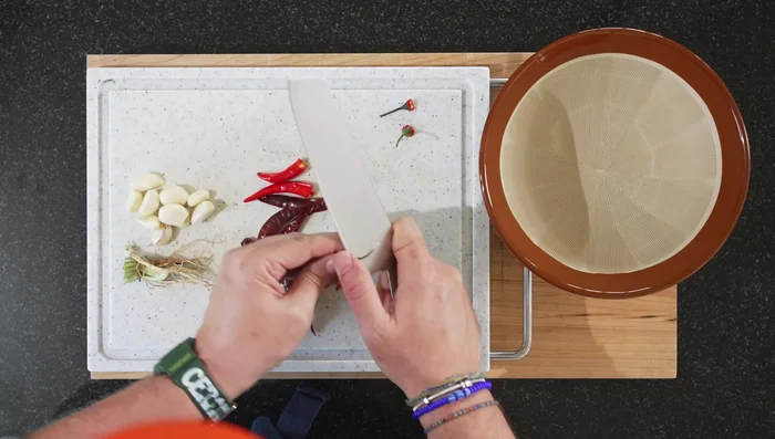 Prepare the paste: Remove stems from fresh chilies. Roughly chop fresh and dried chilies, garlic, and coriander stems. Combine all in a mortar and pestle and grind into a paste. (This takes about 5 minutes)