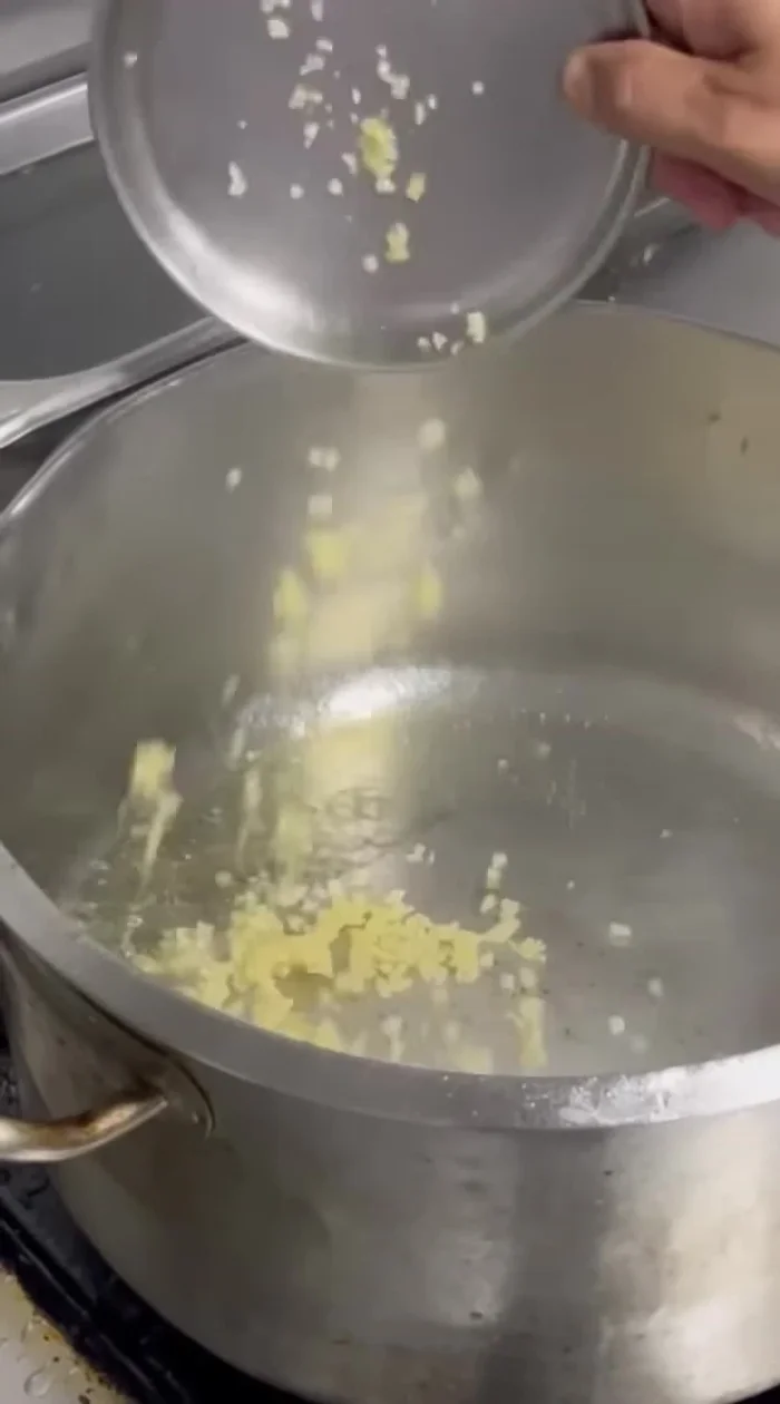 Pour oil into a vessel and saute the chopped garlic.