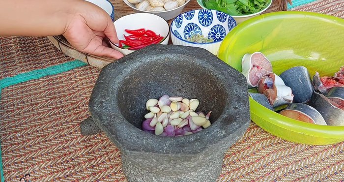 Pound the curry paste: shallots, garlic, chili peppers, and lemongrass.