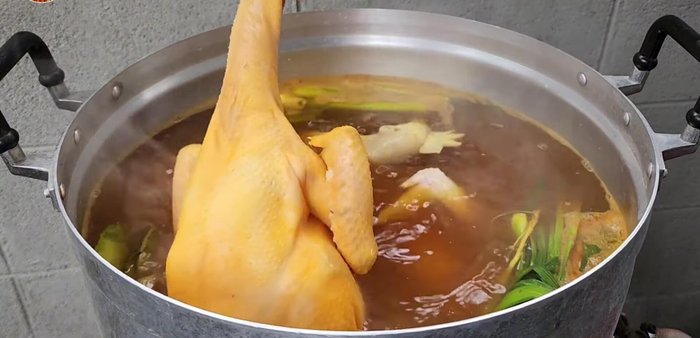 Add the chicken and internal organs to the pot. Simmer over medium heat for approximately 20 minutes, then flip the chicken for even coloring.