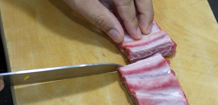 Cut the pork ribs into strips, ensuring there's a gap between each rib for easier cooking.