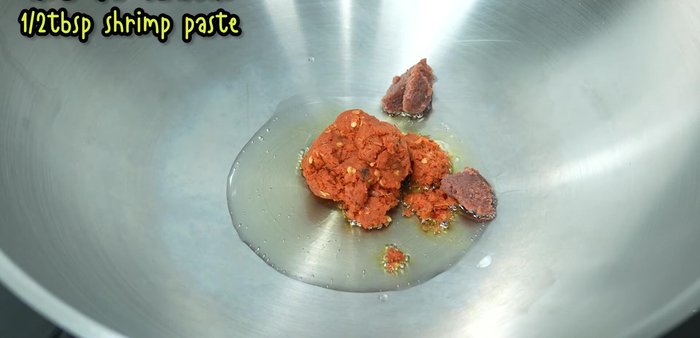 Add red curry paste, shrimp paste, and pounded red chili peppers. Stir-fry until fragrant.