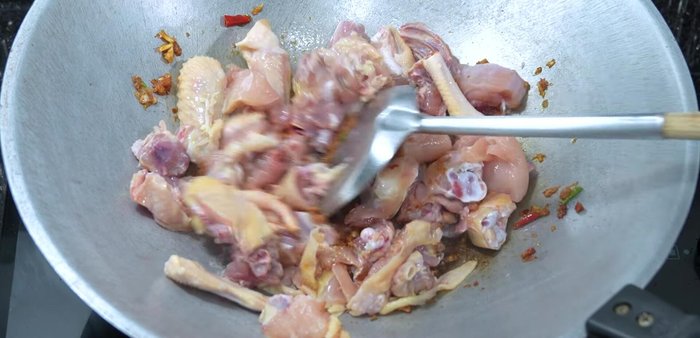 Add chicken and stir-fry until partially cooked, then add kaffir lime leaves and sliced galangal.