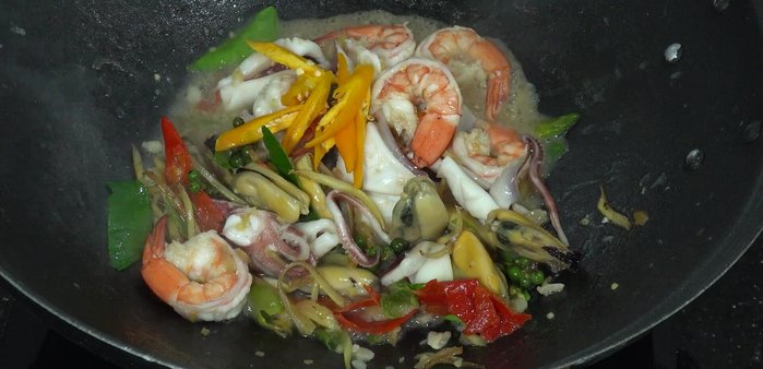 Add 1 yellow chili (cut diagonally), 1 red chili (cut diagonally), and 20 grams of basil leaves. Stir-fry until everything is cooked and well combined.