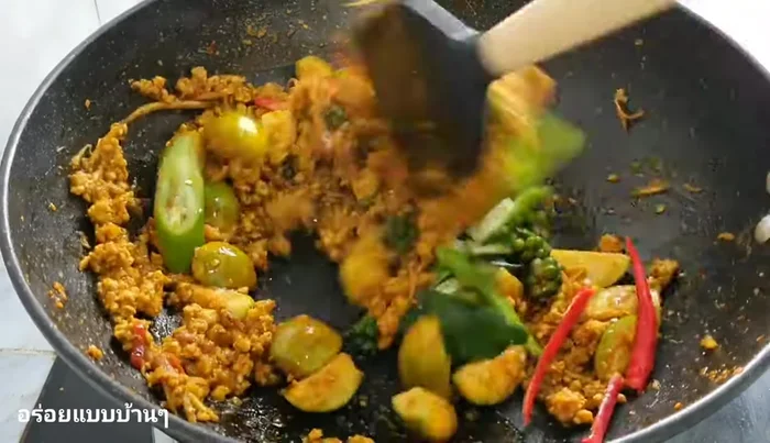 Add kaffir lime leaves, pepper, and green/red chilies. Stir-fry.