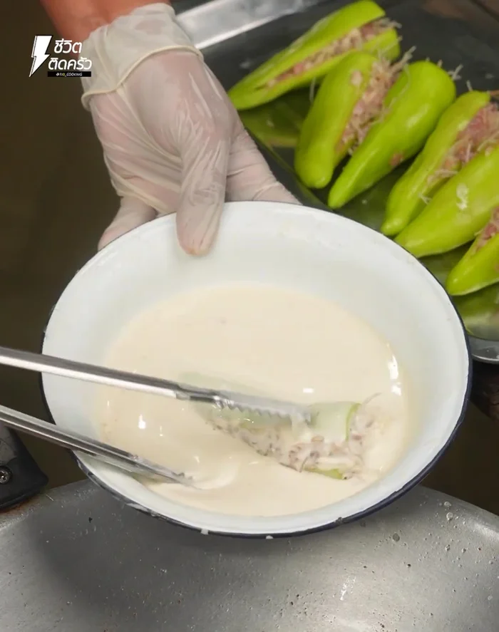Dip the stuffed bell peppers in the flour batter. (141.04)