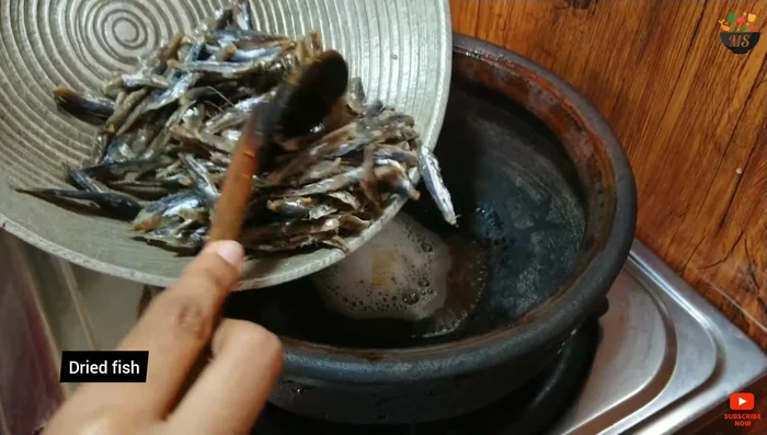 Heat coconut flakes in a pot until the oil is hot. Add dried fish and fry.
