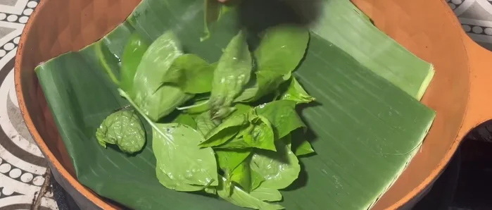 Prepare the pan: Line the bottom with banana leaves, fold twice, and add basil and other desired vegetables. (118.439)