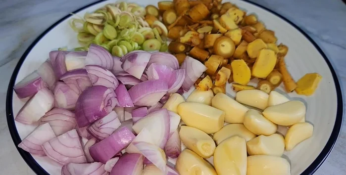 Prepare aromatics: finely chop lemongrass, shallots, garlic, chilies, galangal, and kaffir lime leaves. (55.399)