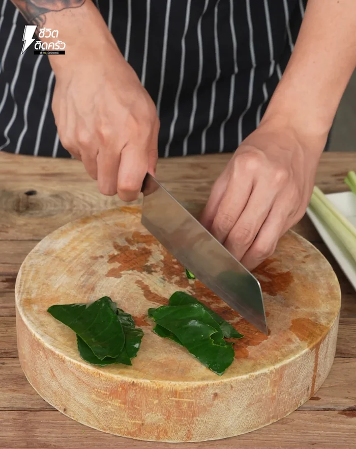 Collect kaffir lime leaves from the garden, wash, and pick only the leaves. Roll and chop the leaves into thin strips.