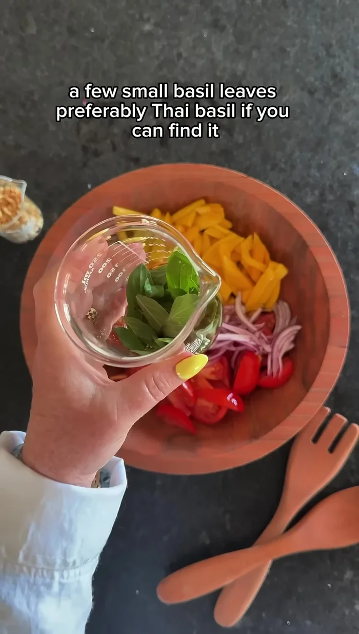 Add the mango, tomatoes, red onions, basil leaves, and roasted peanuts to the bowl with the dressing.