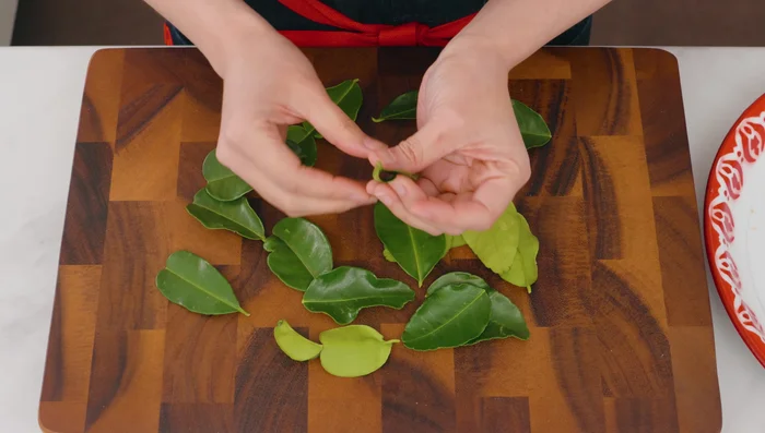 Prep the lime leaves: Wash and thoroughly dry the leaves. Tear off the center stems and tear each leaf half into two. (122.96)