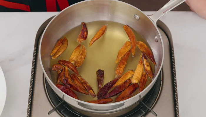 Fry the chilies: Add dried chilies and fry until slightly darker in color and crispy. (488.759)