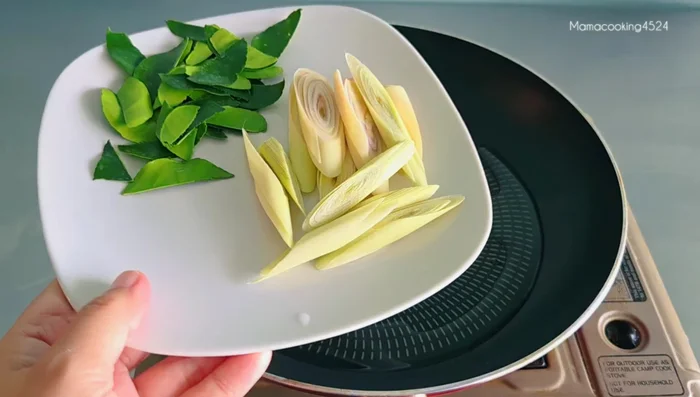 Heat vegetable oil in a pan. Add kaffir lime leaves and lemongrass; stir-fry until fragrant.