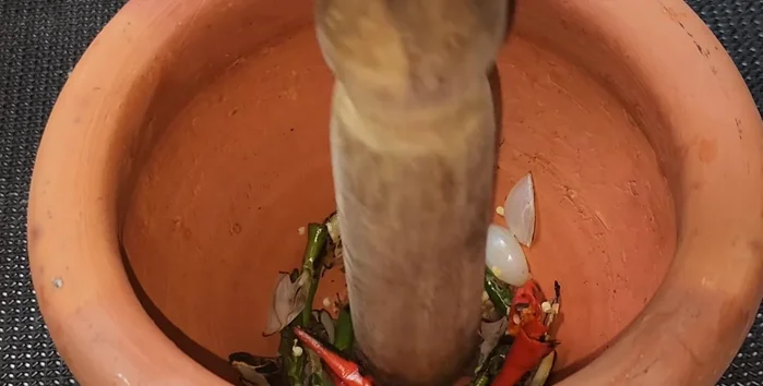 Pound the roasted shallots, garlic, chilies, and shrimp paste in a mortar and pestle until well combined.