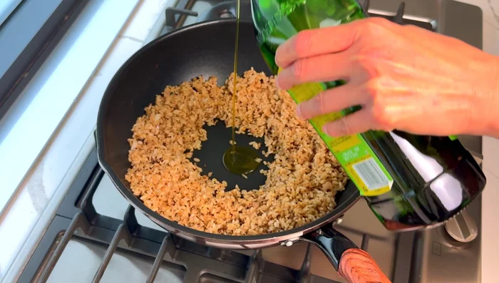 Push rice to the edges, add oil, crack an egg into the center, and stir slightly.