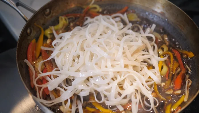 Add cooked rice noodles and shredded carrots. Toss to combine.