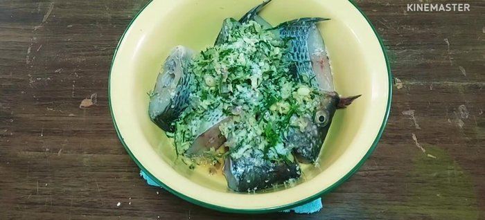 Combine tilapia and herbs: Mix the pounded herbs with the tilapia, adding salt, MSG, and seasoning powder. Massage the seasoning into the fish.