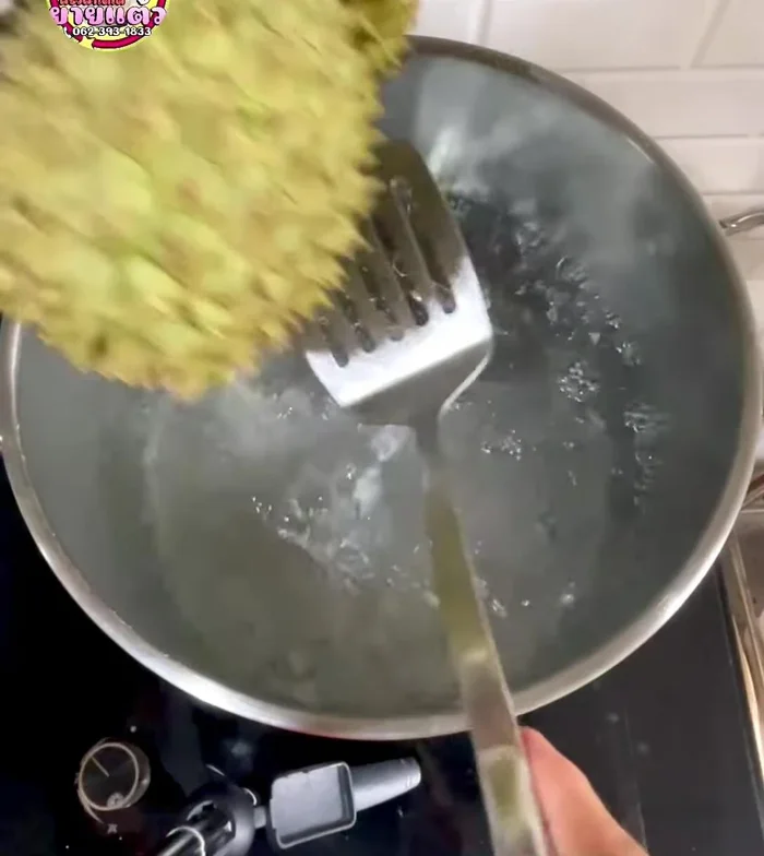 Add the durian to the boiling water. Press down to ensure it's fully submerged.