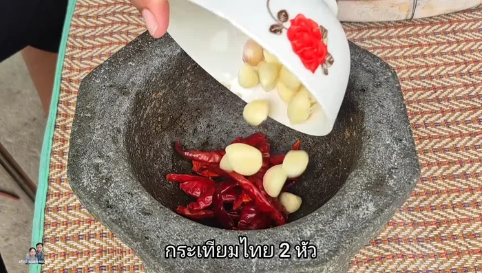 Pound 15 dried chilies and 2 cloves of Thai garlic together in a mortar.