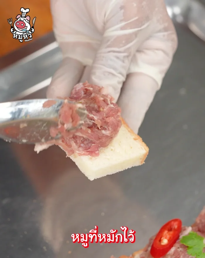Place marinated pork on the bread slices. Decorate with coriander and red chili.