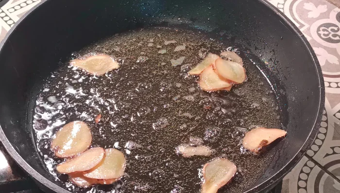 Heat the Teflon pan on medium heat, then reduce to low heat. Add 100ml of oil and sliced ginger.