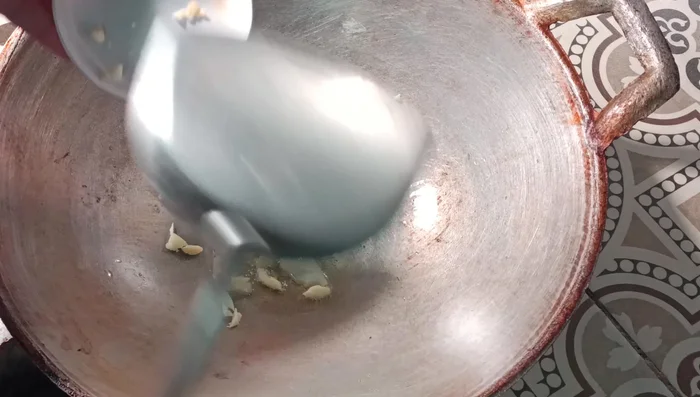 Heat oil in a wok or frying pan. Add the garlic and fry until slightly yellow.