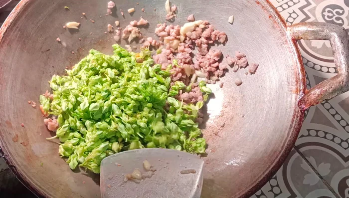 Add the sesbania flowers and stir-fry until well combined.