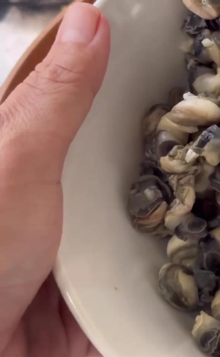 Rinse the snails with clean water 1-2 times. Add water to cover and add orange juice and soy sauce. Soak for 10 minutes to remove fishy smell.