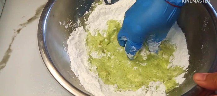 Gradually add pandan water (700ml) to the dry ingredients, kneading the dough until the sugar dissolves.