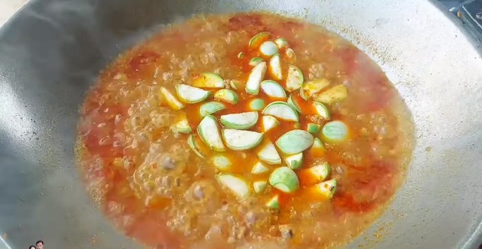 Add cherry tomatoes and the soaked and rinsed eggplant. Ensure the soup is boiling before adding the eggplant to prevent it from turning black.