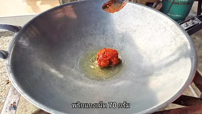 Add a little bit of plants (likely aromatics like shallots, garlic, etc.) and then add 1 full spoonful of red curry paste (about 70 grams). Stir-fry until fragrant.