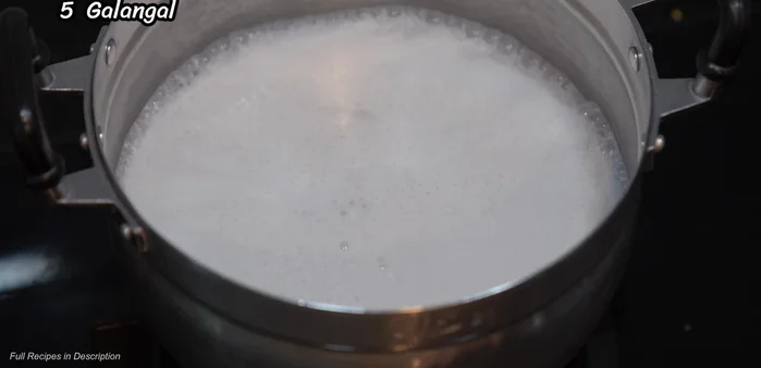 Add galangal, lemongrass, shallots, and kaffir lime leaves to the boiling coconut milk.