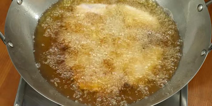Add the chicken wings to the hot oil, arranging them neatly to prevent sticking. Fry over medium-low heat, stirring occasionally to ensure even cooking and browning.
