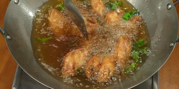 Remove the chicken wings and let them drain the oil. Garnish with fried lemongrass and kaffir lime leaves.