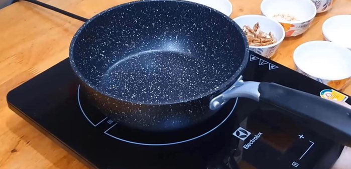 Make caramel coated mixed nuts by adding water and sugar to a pan. Add salt.