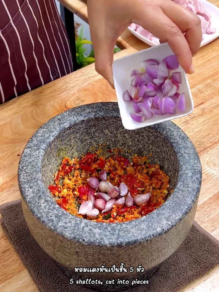 Add 1 tablespoon of garlic cloves and 5 small shallots. Pound everything until finely ground.